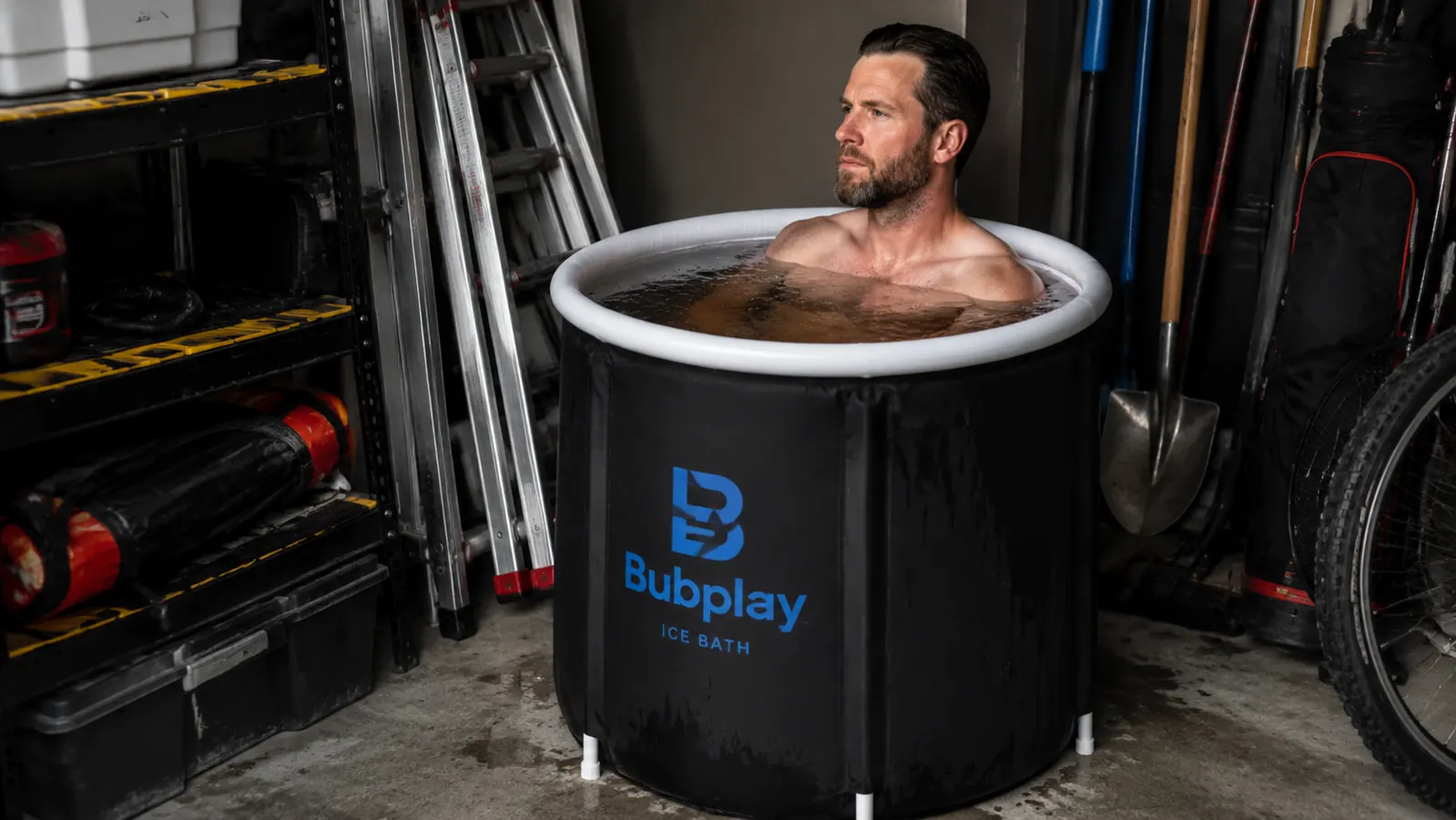 Black round cold plunge tub set up in a garage next to a workbench and tackle boxes