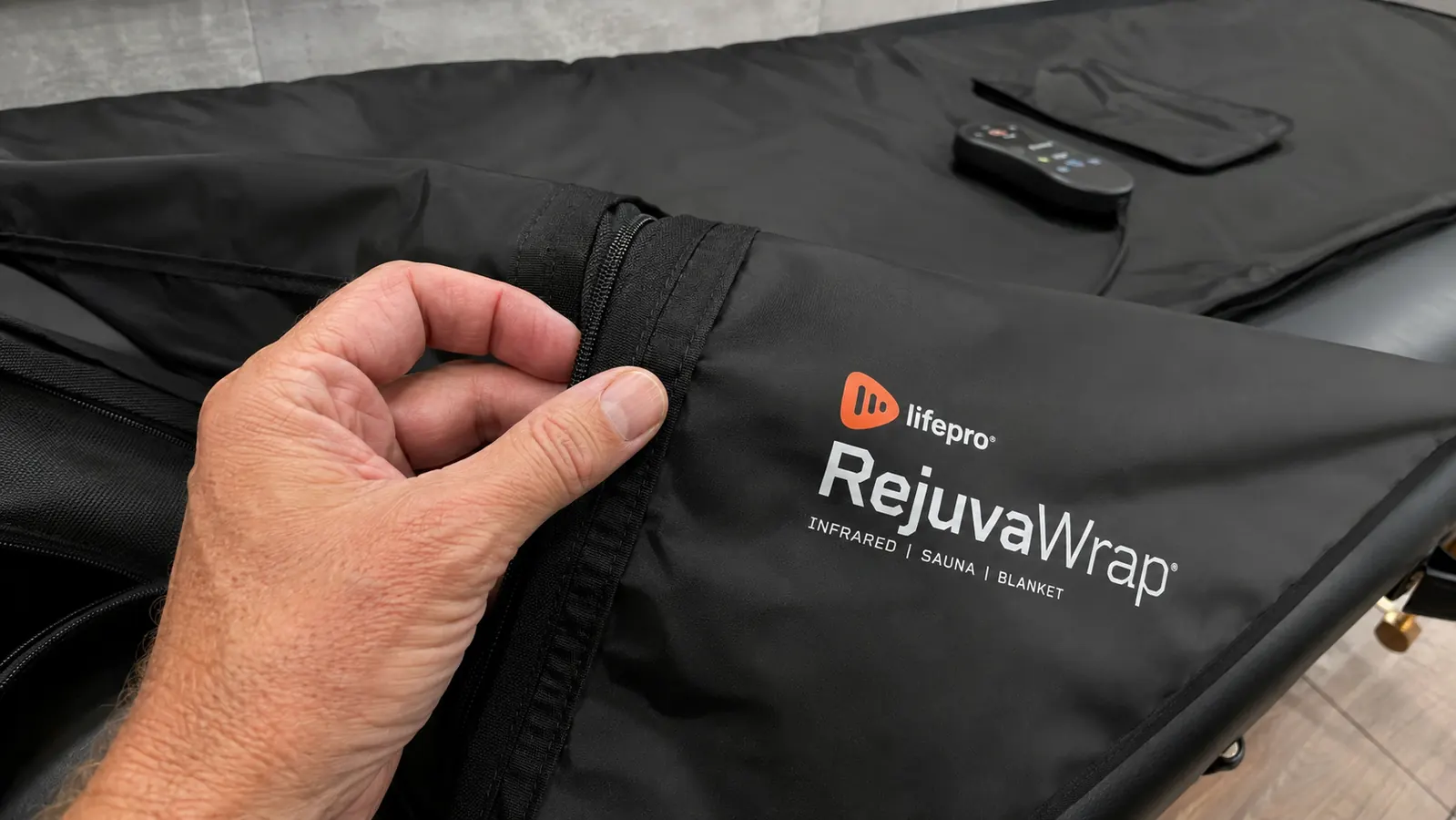 Close-up of a hand checking the stitching on the zipper seam of the Lifepro RejuvaWrap infrared sauna blanket